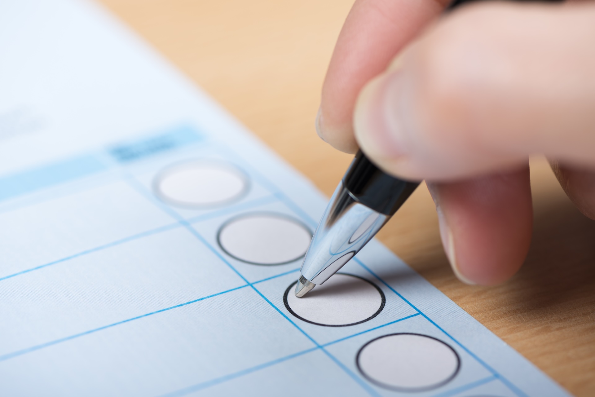 Eine Hand hat einen Kugelschreiber in der Hand und füllt einen Briefwahlstimmzettel aus. Foto: no limits pictures/GettyImages