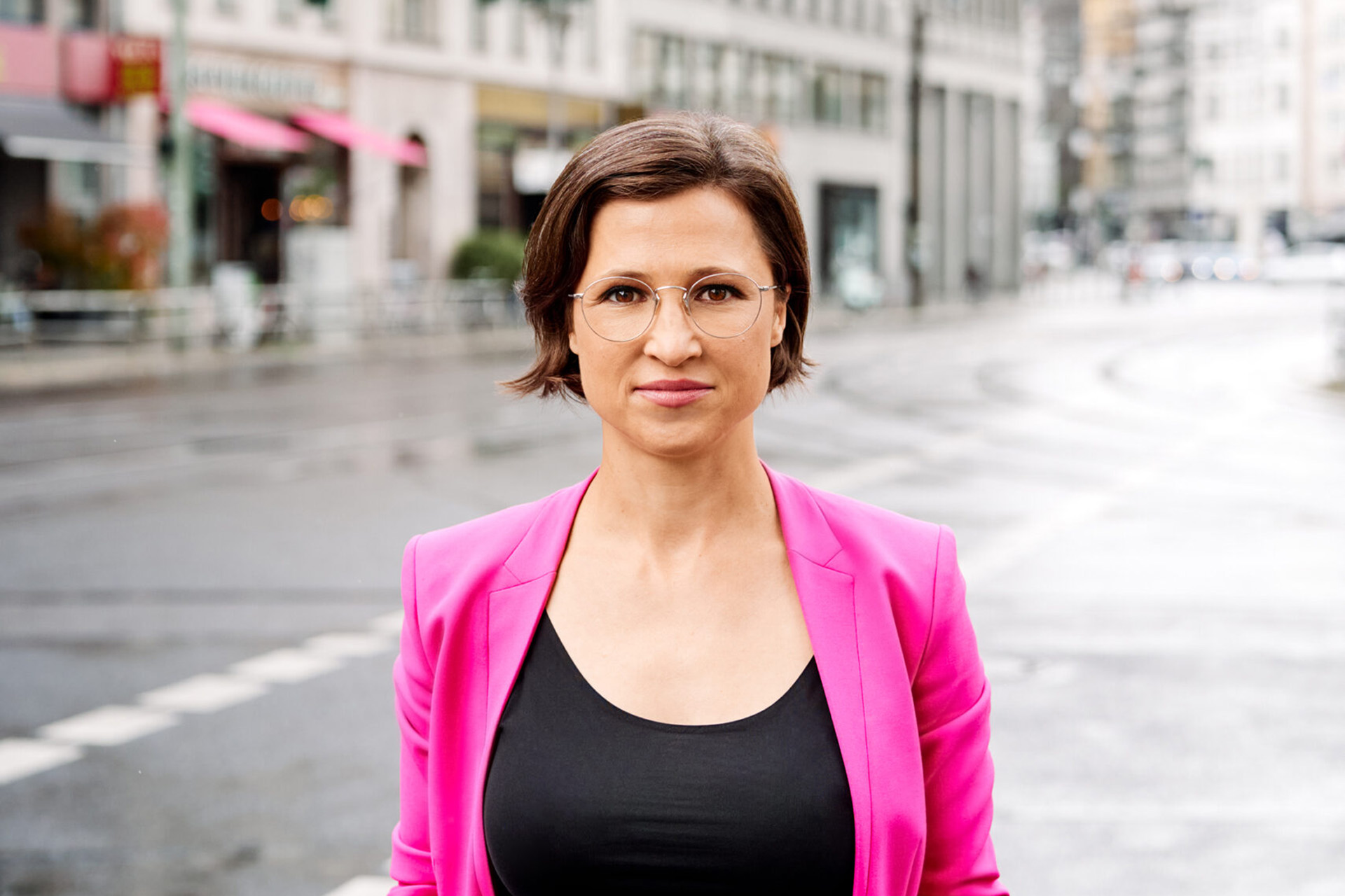 Ein Portraifoto von Hannah Neumann, grüne Abgeordnete des Europäischen Parlaments. Sie steht auf einer Straße und trägt einen pinken Blazer. Foto: Sapna Richter