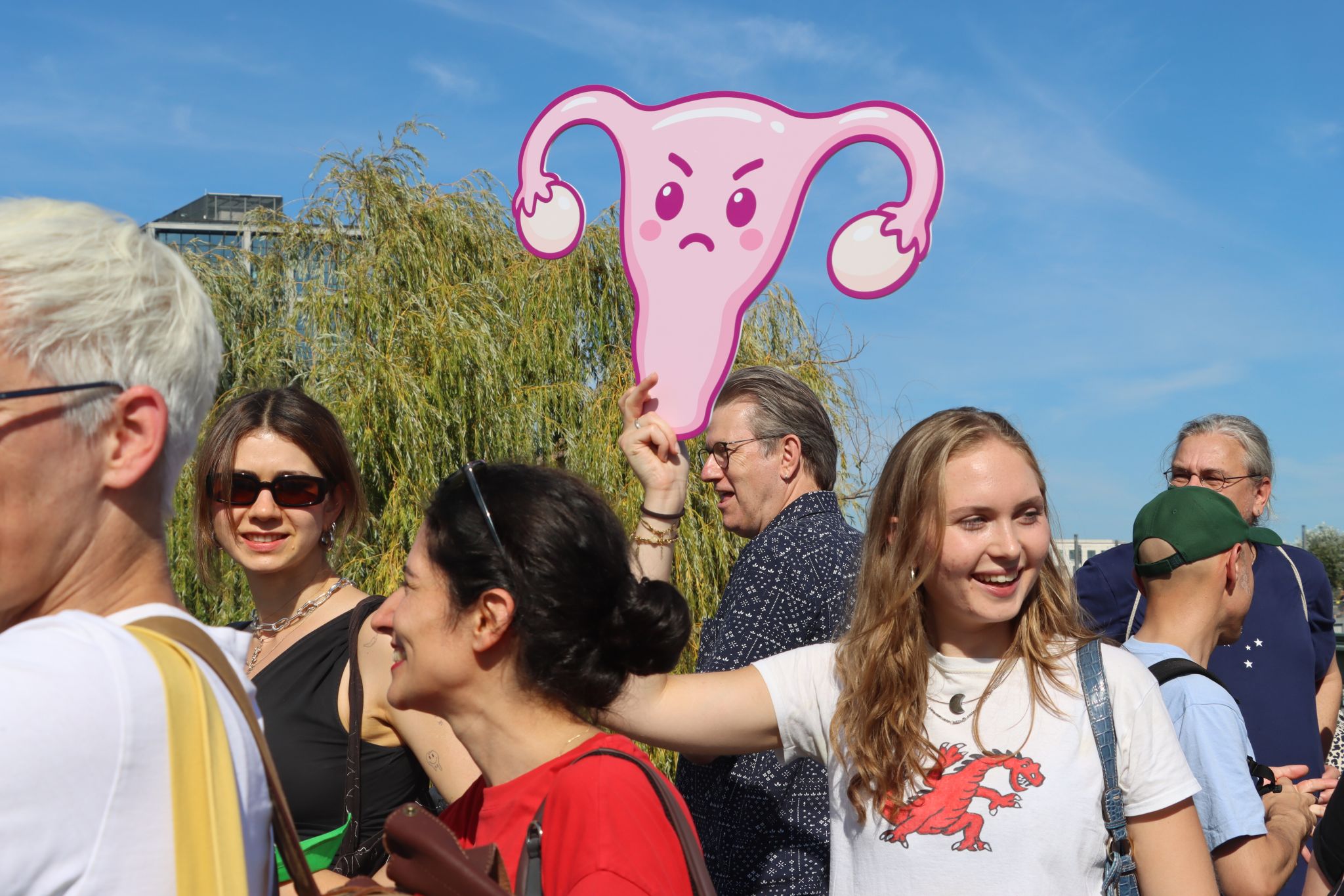 Mehrere Personen bei einer Demonstration, eine junge Frau hält ein Bild eines weiblichen Uterus' hoch.