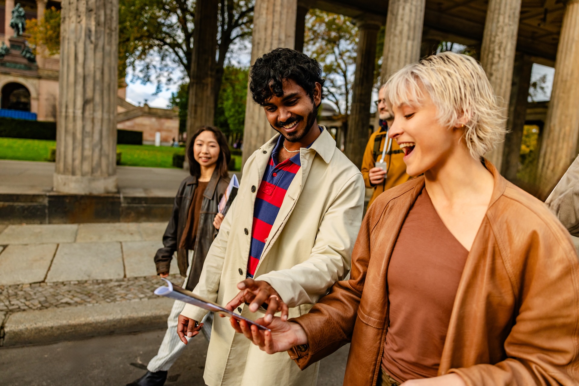 Mehrere Personen gehen nebeneinander, sie lachen und schauen auf ein Smartphone Foto: South Agency/GettyImages
