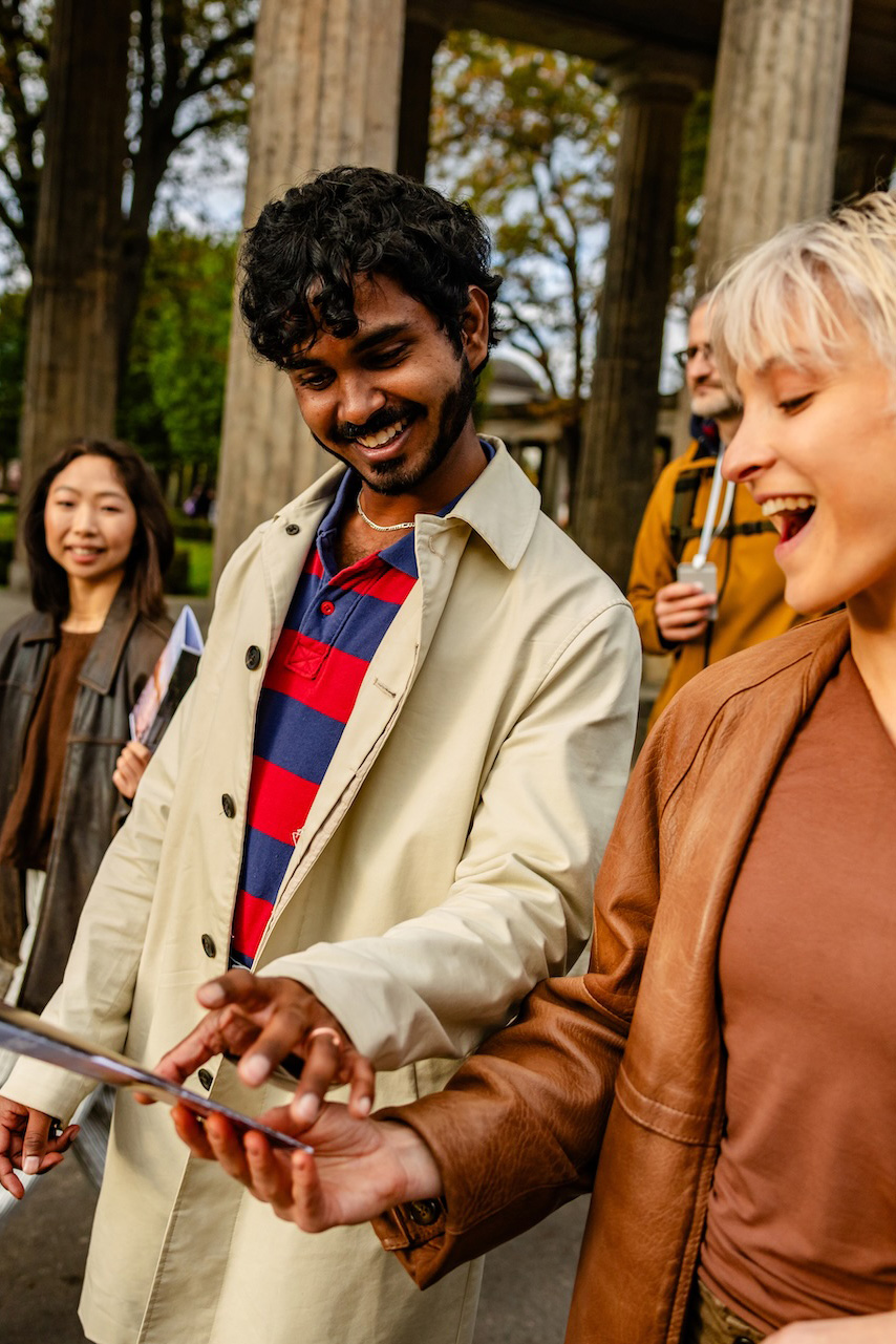Zwei Personen gehen eine Straße in Berlin entlang, sie lachen und schauen auf einen Flyer. Foto: South Agency/GettyImages