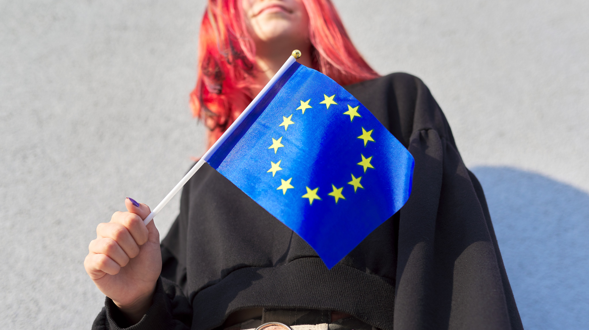 Eine junge Frau, deren Gesicht nicht erkennbar ist, hält eine kleine Europaflagge in der Hand. Foto: Valerii Honcharuk via Getty Images
