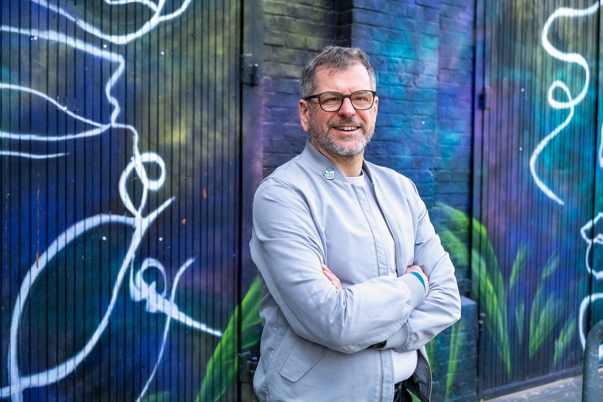 Werner Graf steht vor einer bunten Graffiti-Wand in Berlin 
