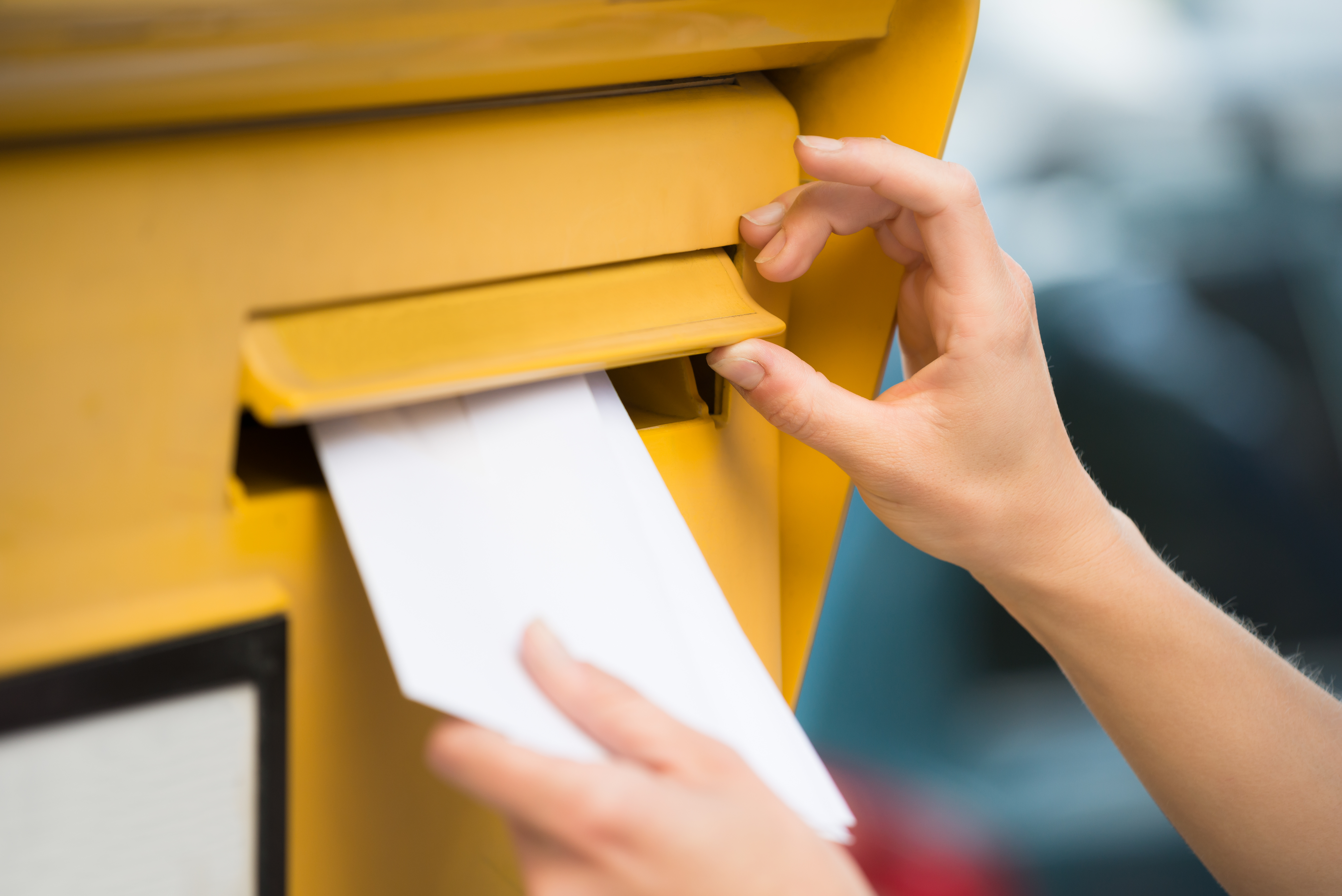 Eine Person, von der außer ihren Händen nichts zu sehen ist schiebt einen Brief in einen Briefkasten. Andrey Popov via Getty Images