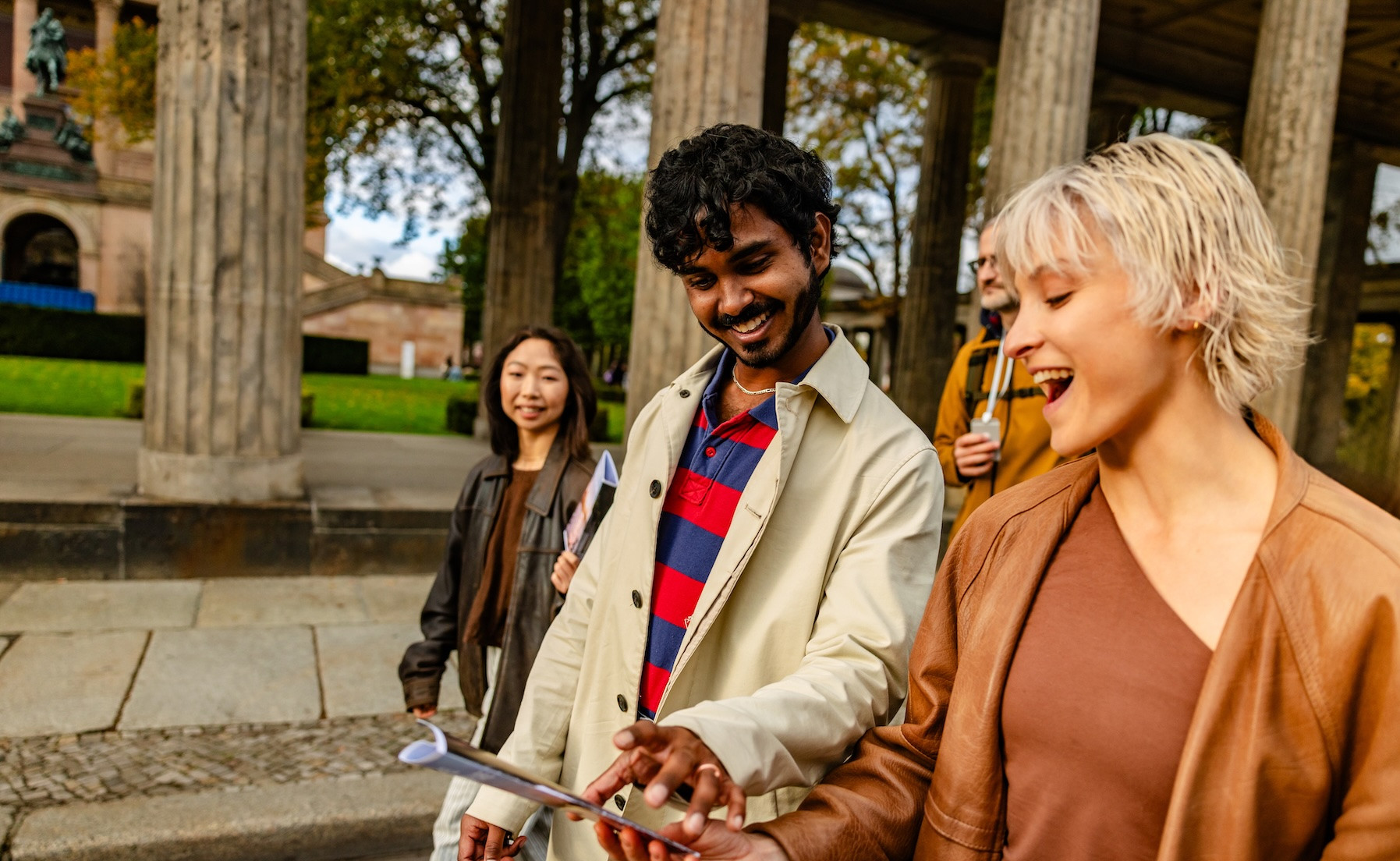 Mehrere Personen gehen nebeneinander, sie lachen und schauen auf ein Smartphone Foto: South Agency/GettyImages