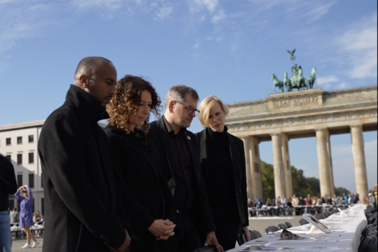Philmon Ghirmai, Bettina Jarasch, Werner Graf und Nina Stahr stehen nebeneinander bei der Gedenkveranstaltung am Brandenburger Tor
