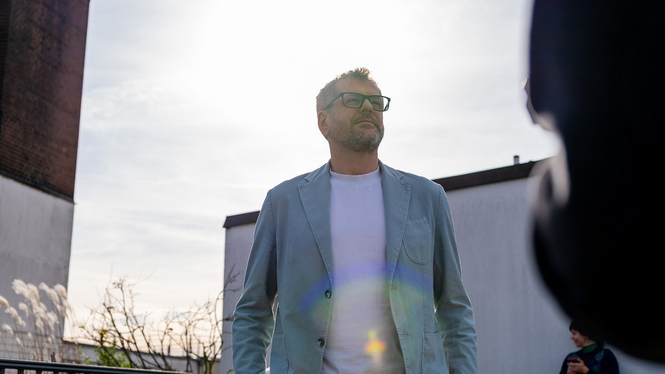 Werner Graf, Grüner Bürgermeisterkandidat, steht auf einem Berliner Hausdach, hinter ihm scheint die Sonne, er schaut in die Ferne.