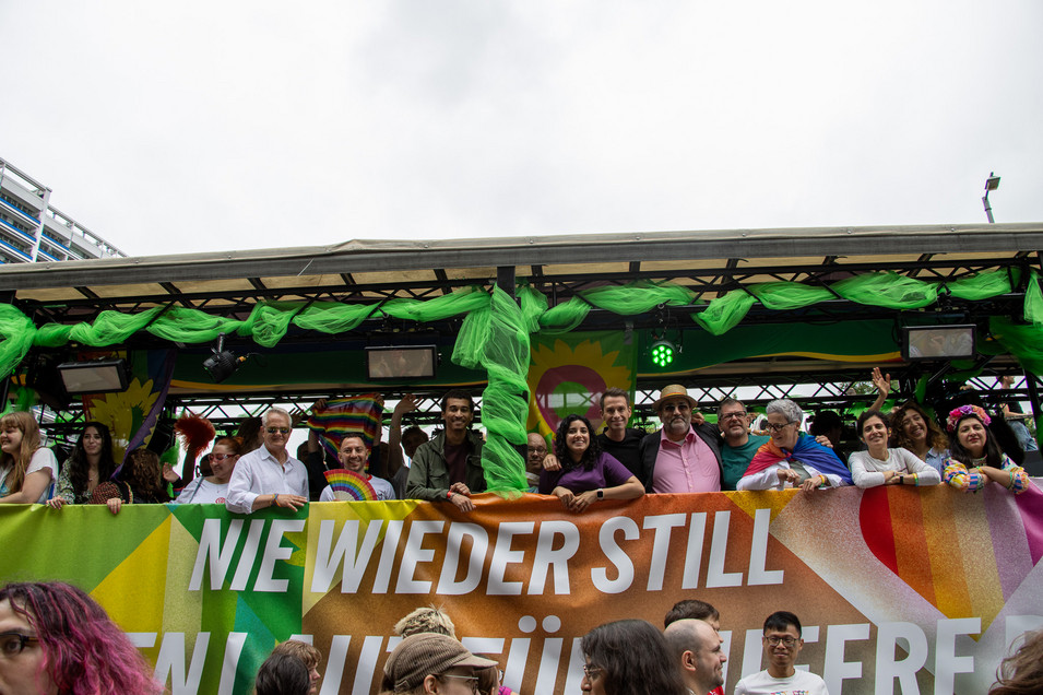 Viele Personen stehen nebeneinander auf einem geschmückten Wagen, an diesem hängt ein Transparent mit der Aufschrift "Nie wieder still. Wir bleiben laut für queere Rechte." Foto: Bündnis 90/Die Grünen Berlin