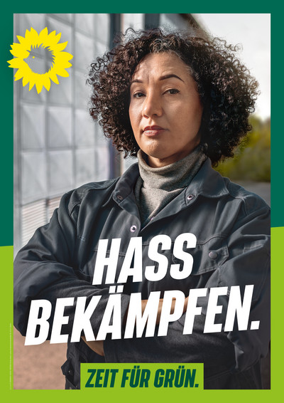 Laternenplakatmotiv der grünen Kampagne für die Wiederholungswahl 2023. Eine Frau blickt mit entschlossenem Blick in die Kamera, sie hält ihre Arme vor ihrem Körper verschränkt. Darunter der Schriftzug "Hass bekämpfen" und in einem grünen Kasten "Zeit für Grün". Bündnis 90/Die Grünen Berlin