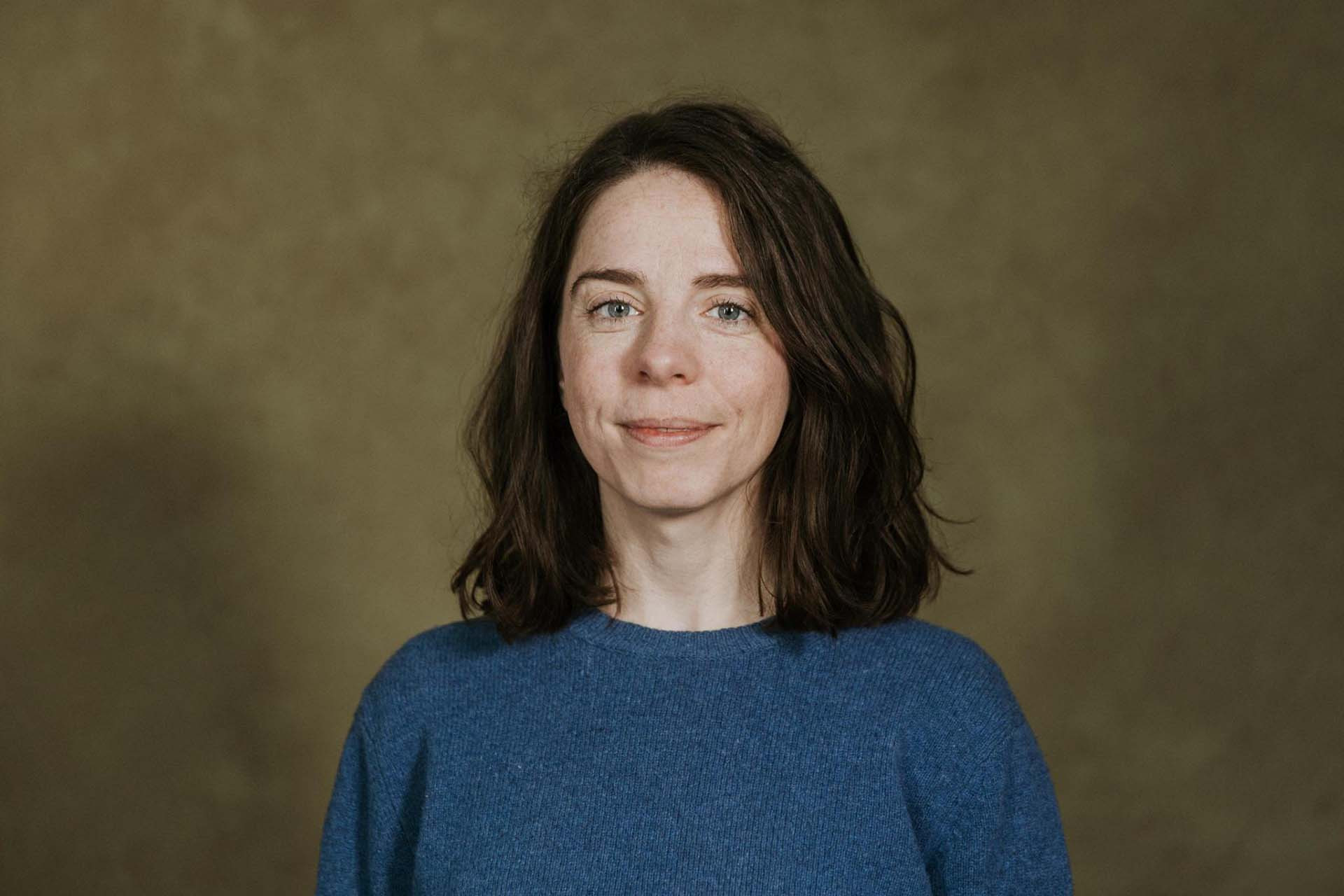 Ein Portraitfoto der Bundestagsabgeordneten Julia Schneider. Sie trägt einen grünen Pullover und blickt in die Kamera.
