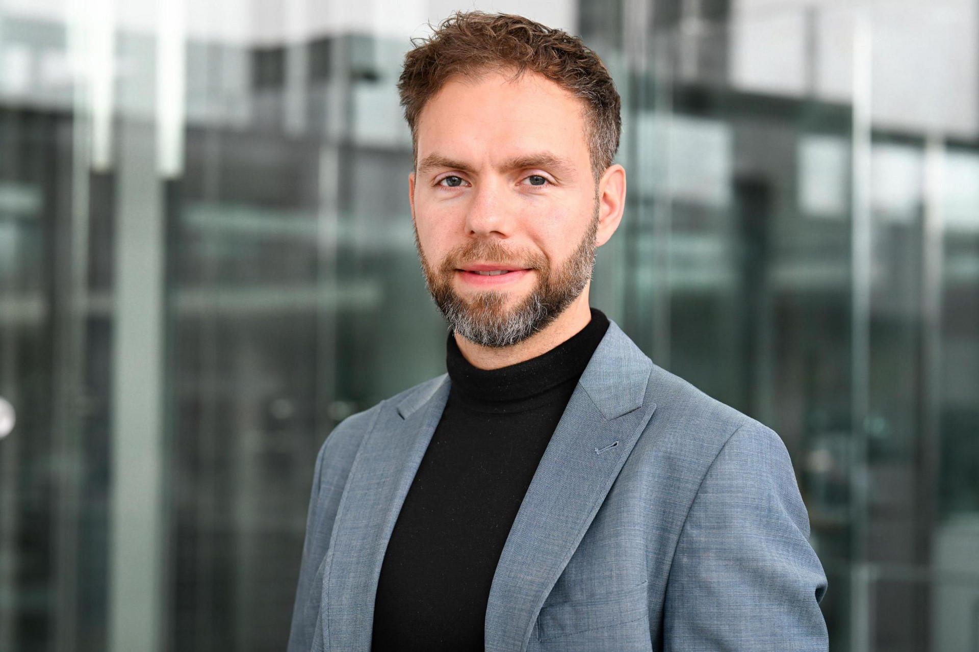 Ein Portraitfoto des Bundestagsabgeordneten Dr. Moritz Heuberger, er trägt einen Rollkragenpullover und ein Sakko und lächelt in die Kamera. Foto: Stefan Kaminski