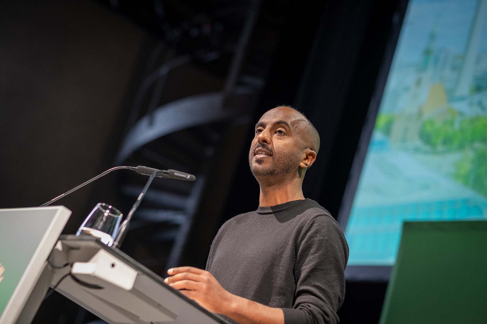 Der Landesvorsitzende Philmon Ghirmai auf der Bühne, er spricht in ein Mikrofon.