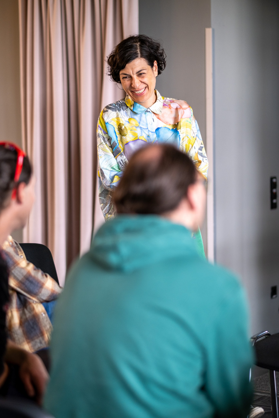 Ein Blick auf die Diskussionen auf dem Grünen Stadtkongress, eine Person steht vorne und lächelt die Teilnehmenden an.
