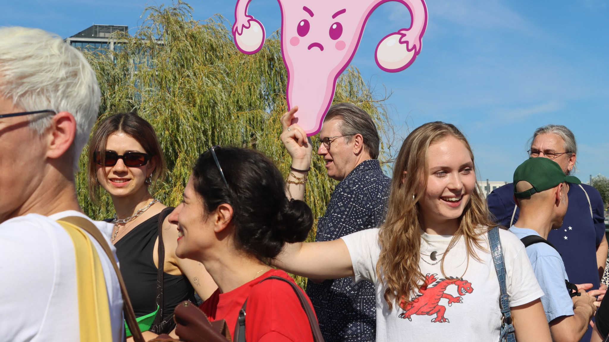 Mehrere Personen bei einer Demonstration, eine junge Frau hält ein Bild eines weiblichen Uterus' hoch. 