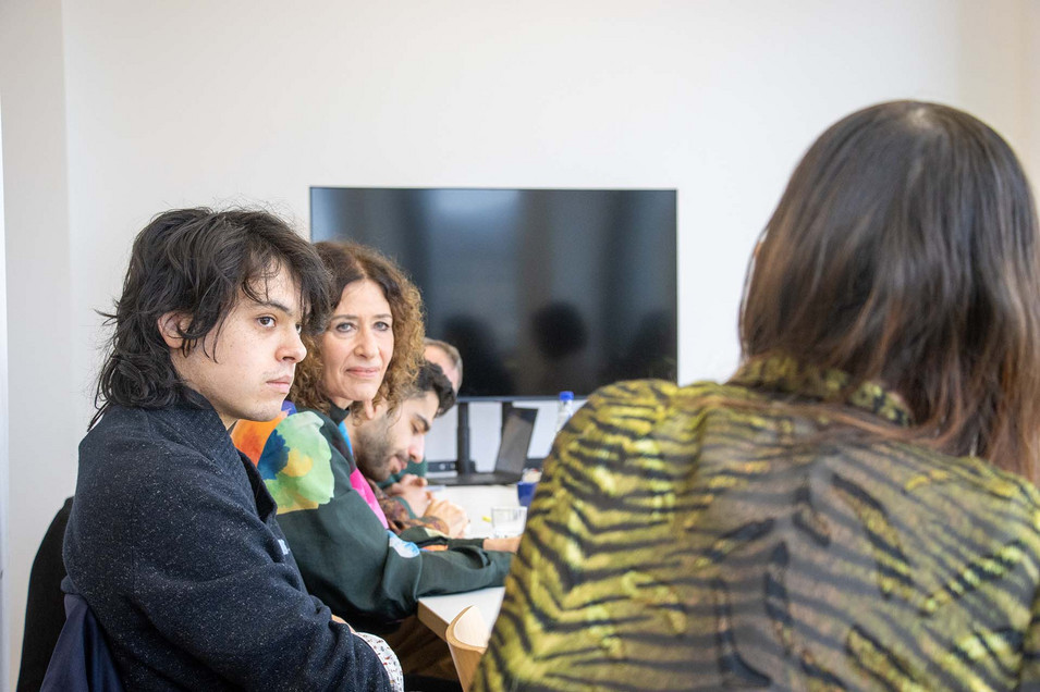 Mehrere Personen sitzen an einem Tisch und sprechen miteinander.