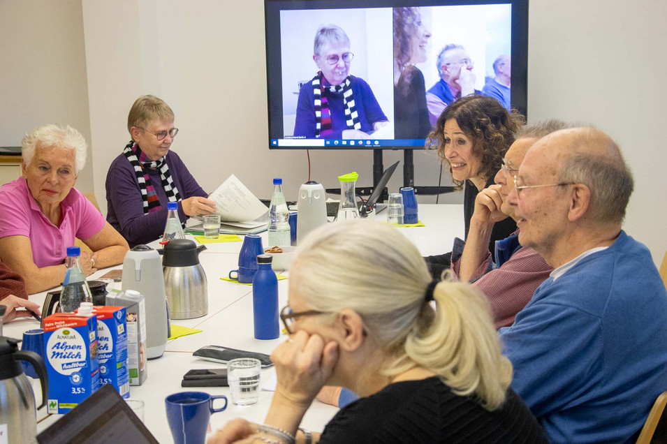 Mehrere Personen sitzen an einem Konferenztisch und sprechen miteinander.