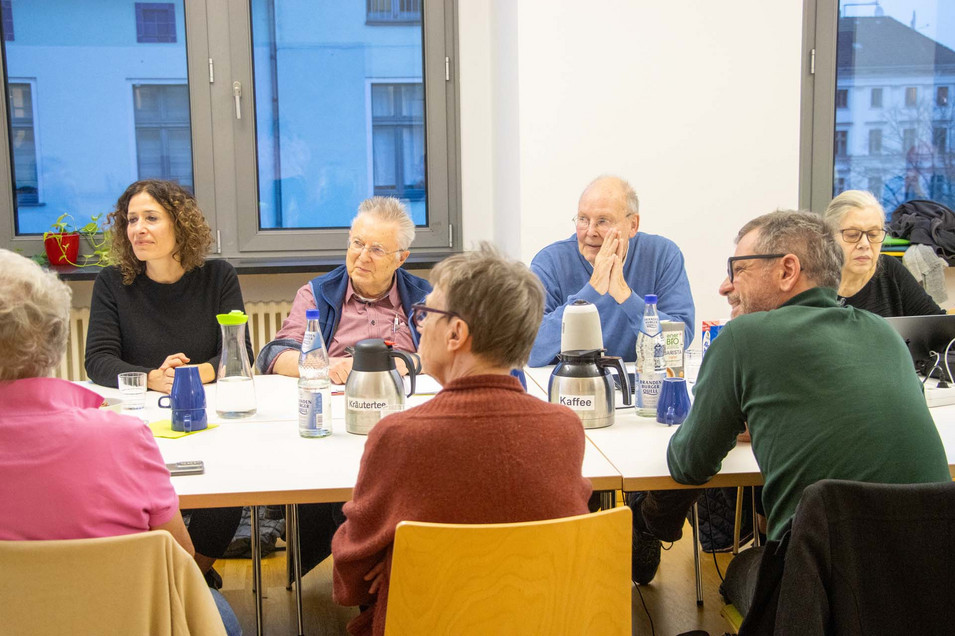Mehrere Personen sitzen an einem Tisch und sprechen miteinander