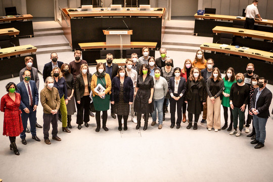 Ein Gruppenfoto der grünen Abgeordneten im Berliner Abgeordnetenhaus. Die Abgeordneten sind von leicht oben aufgenommen und stehen im Halbkreis im Plenarsaal des Abgeordnetenhauses. Vincent Villwock/Grüne Fraktion Berlin