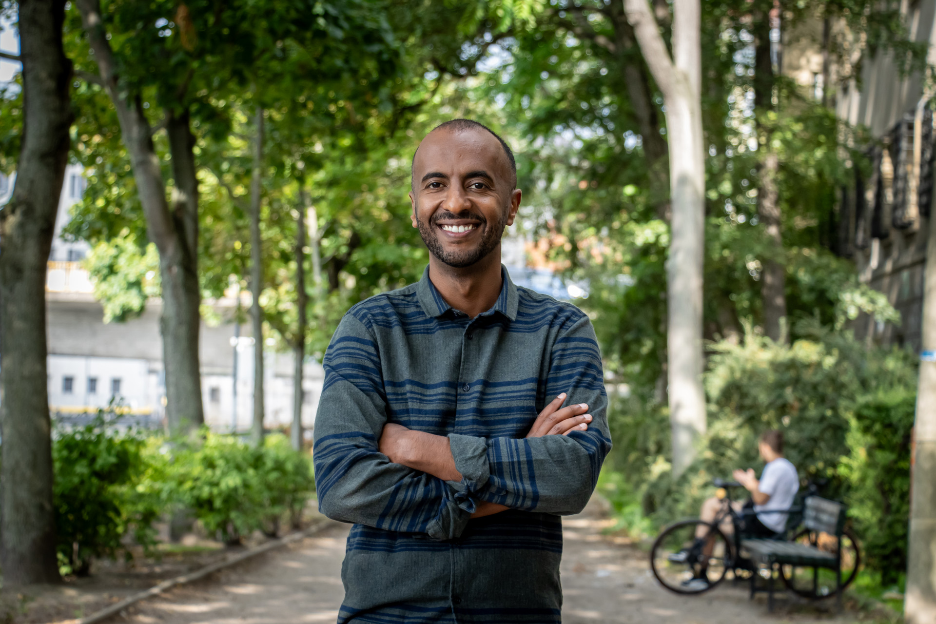 Portrait von Philmon Ghirmai, Landesvorsitzender von Bündnis 90/Die Grünen Berlin vor einer begrünten Straße.  Foto: Bündnis 90/Die Grünen Berlin