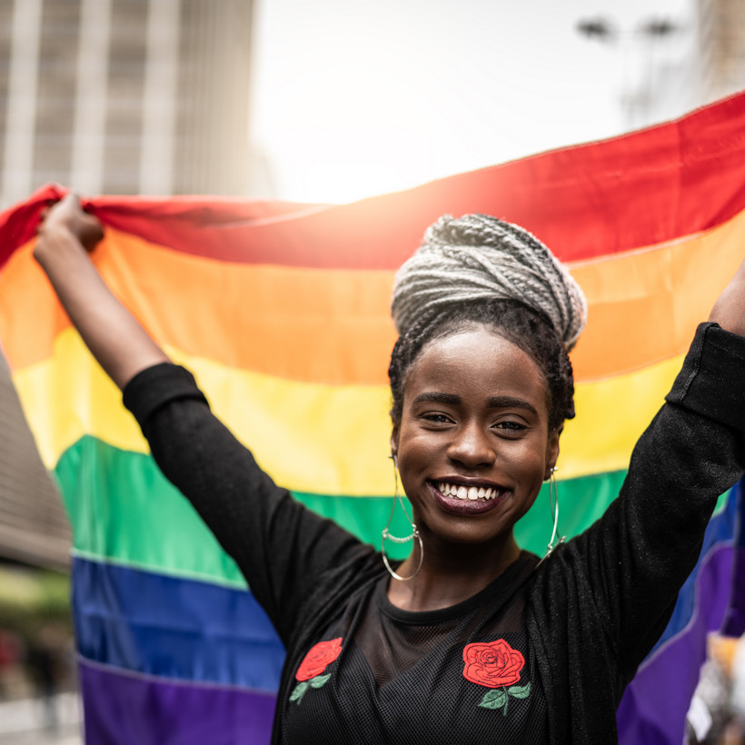 Eine Frau hält eine LGBTQ+ Fahne und lächelt FG Trade via Getty Images