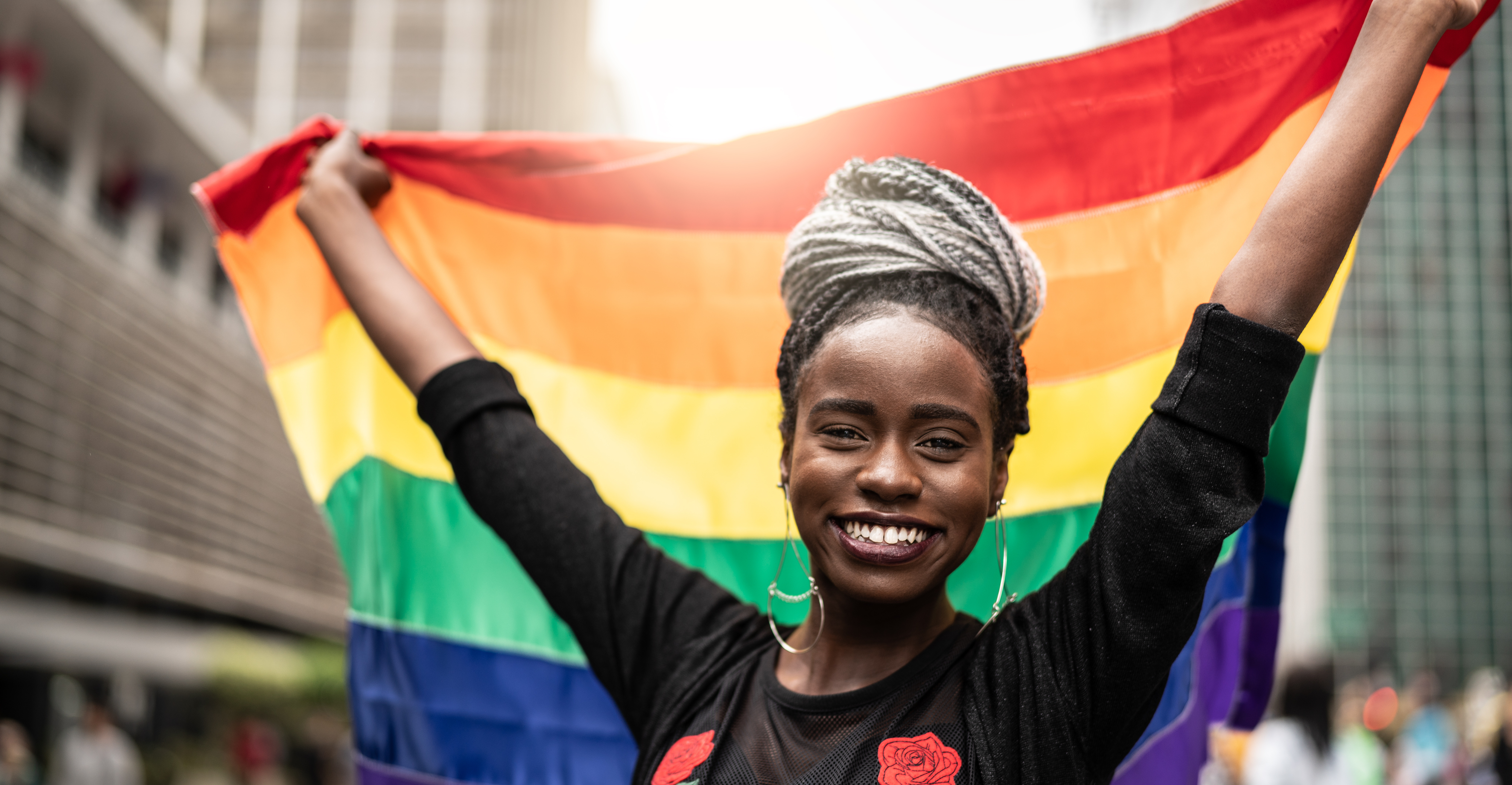 Eine Frau hält eine LGBTQ+ Fahne und lächelt FG Trade via Getty Images