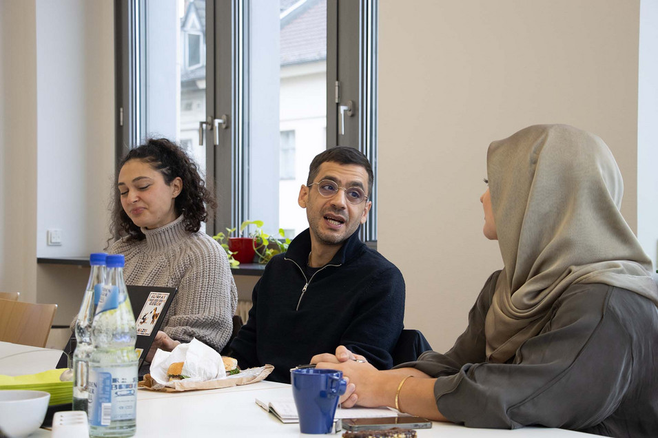 Austausch auf dem BIPoC-Treffen mit Ario Mirzaie, MdA: Mehrere Personen sitzen an einem Tisch und sprechen miteinander.