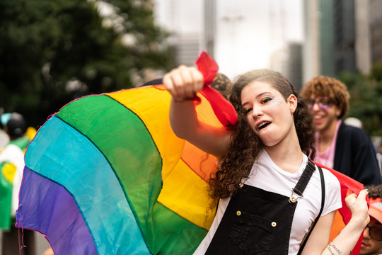Eine Frau mit LGBTQ+ Fahne tanzt auf der Straße Getty