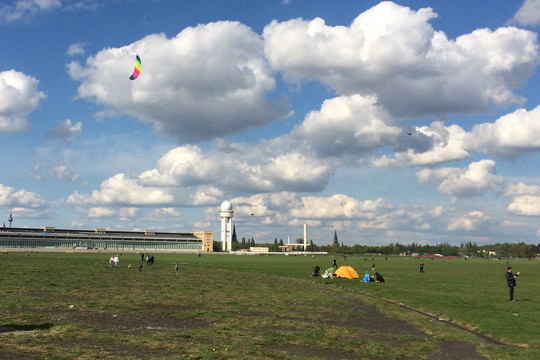 Das Tempelhofer Feld in Berlin an einem sonnigen Tag, im Hintergrund ist das ehemalige Flughafengebäude Tempelhof abgebildet.