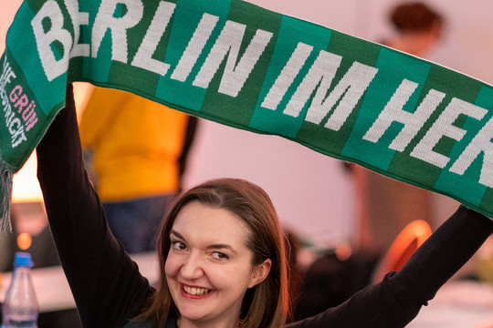 Eine Frau hält einen Schal in die Höhe, auf dem steht "Berlin im Herzen"