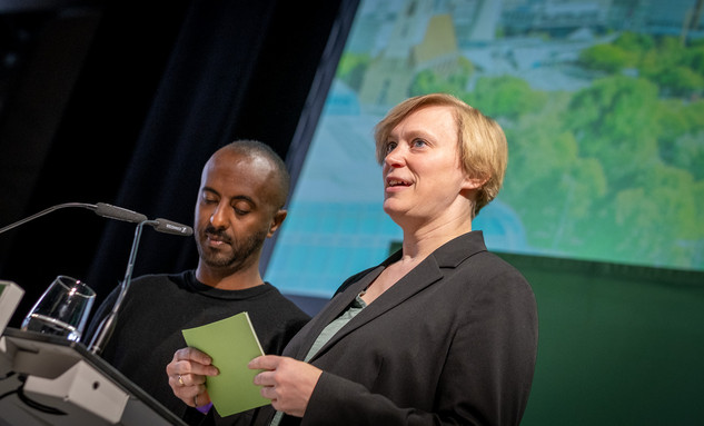 Die Landesvorsitzenden Philmon Ghirmai und Nina Stahr stehen nebeneinander auf einer Bühne. Foto: Bündnis 90/Die Grünen Berlin