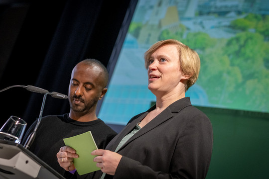 Die Landesvorsitzenden Philmon Ghirmai und Nina Stahr stehen nebeneinander auf einer Bühne. Foto: Bündnis 90/Die Grünen Berlin