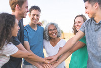 Eine Gruppe von Personen steht im Kreis und legen die Hände aufeinander.