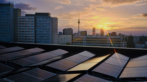 Die Berliner Skyline im Sonnenuntergang, im Vordergrund Solar-/Photovoltaik-Anlagen auf einem Hausdach. Foto: Bündnis 90/Die Grünen Berlin