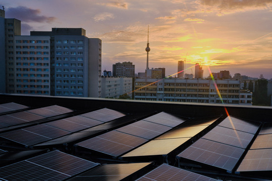 Die Berliner Skyline im Sonnenuntergang, im Vordergrund Solar-/Photovoltaik-Anlagen auf einem Hausdach. Foto: Bündnis 90/Die Grünen Berlin