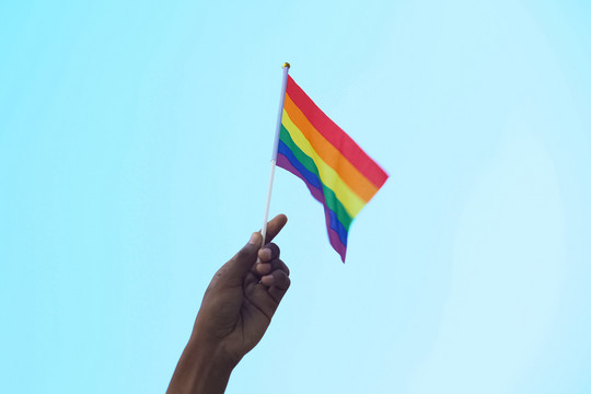 Eine Regenbogenfahne wird von einer Hand in die Höhe gehalten Motortion via Getty Images