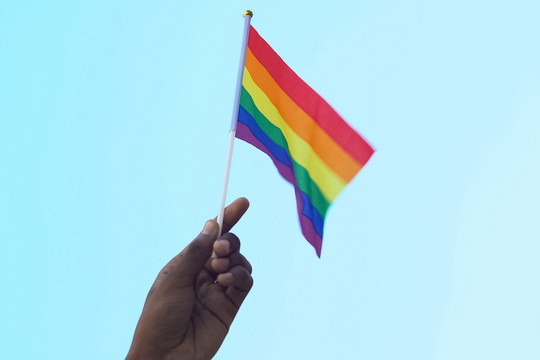 Eine Regenbogenfahne wird von einer Hand in die Höhe gehalten Motortion via Getty Images