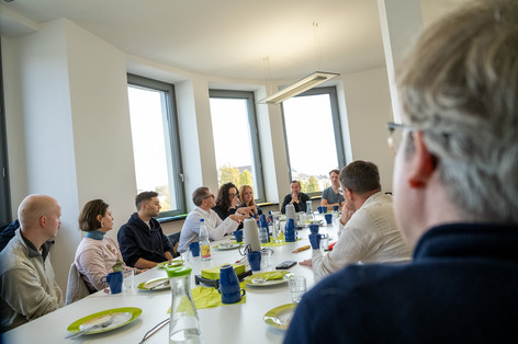 Ein langer Tisch, an dem viele Personen sitzen, sie sind im Gespräch vertieft. Mit dabei: Werner Graf. 