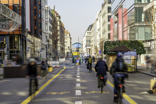 Die Friedrichstraße in Berlin, auf der Straße kleben gelbe Fahrmarkierungen, die Straße ist ausschließlich von Radfahrenden befahren. Der Blickwinkel verläuft in die Straße hinein, links und rechts am Bildrand sind einige Geschäfte in der Friedrichstraße und Begrünung erkennbar. Ivo Gretener via Getty Images
